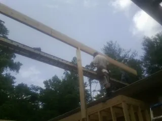 Carpenter setting a ridge beam over a new addition frame — Ice Dam Removal by Roofing Brothers in Darien Center