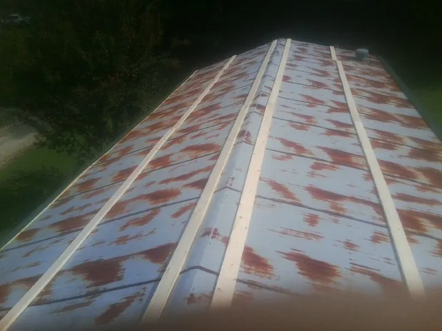 Rusted metal roof panels with new wood purlins before replacement — Storm Damage Roof Repair in Darien Center by Roofing Brothers