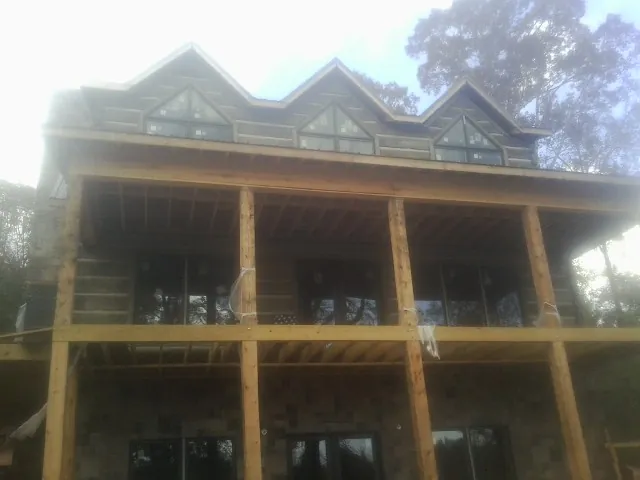 Dormers and porch framing on a large log home under construction — Roof Coating work by our crew in Darien Center