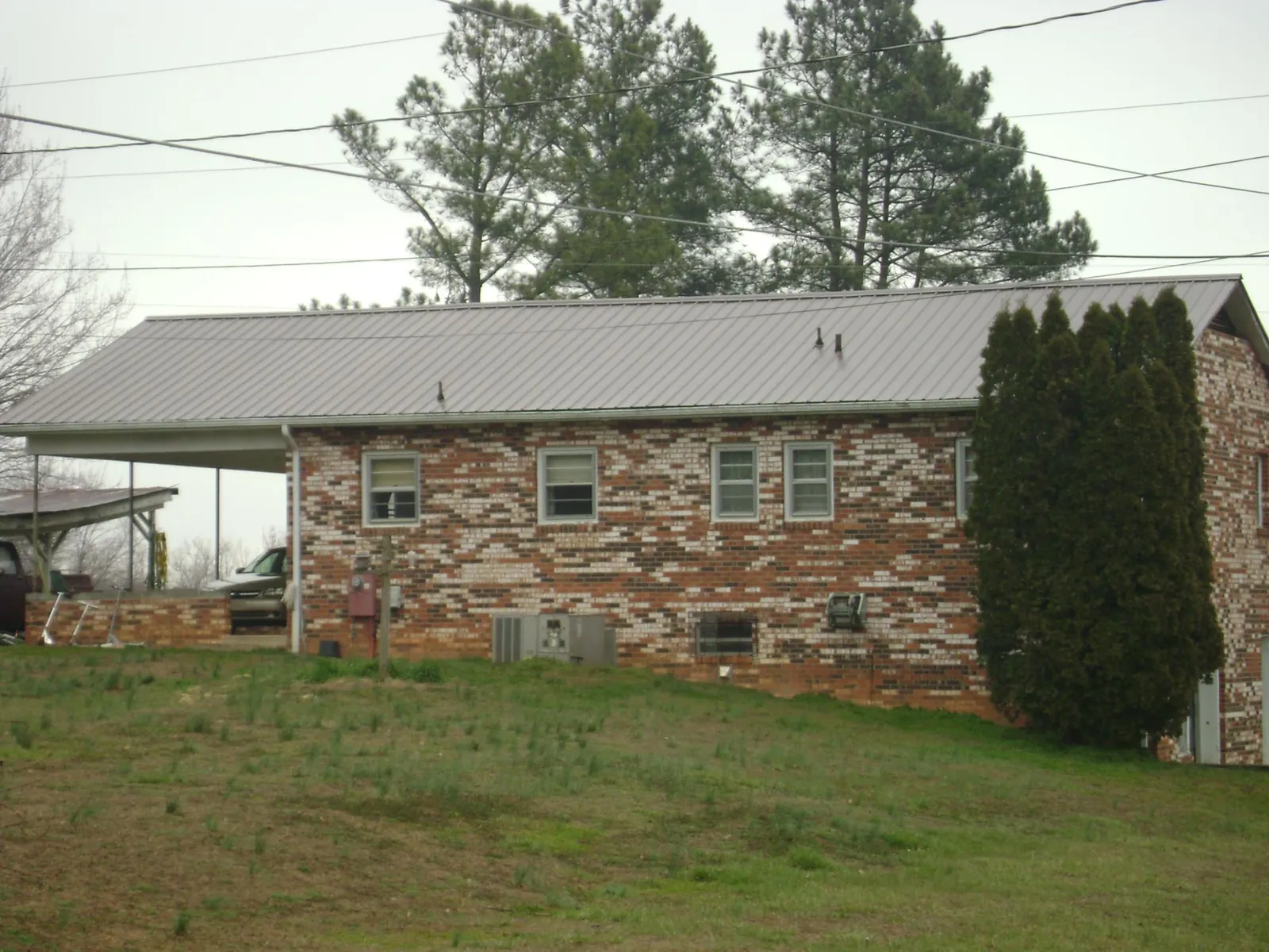 Gray metal roof on a brick split level home with a carport in Darien Center
