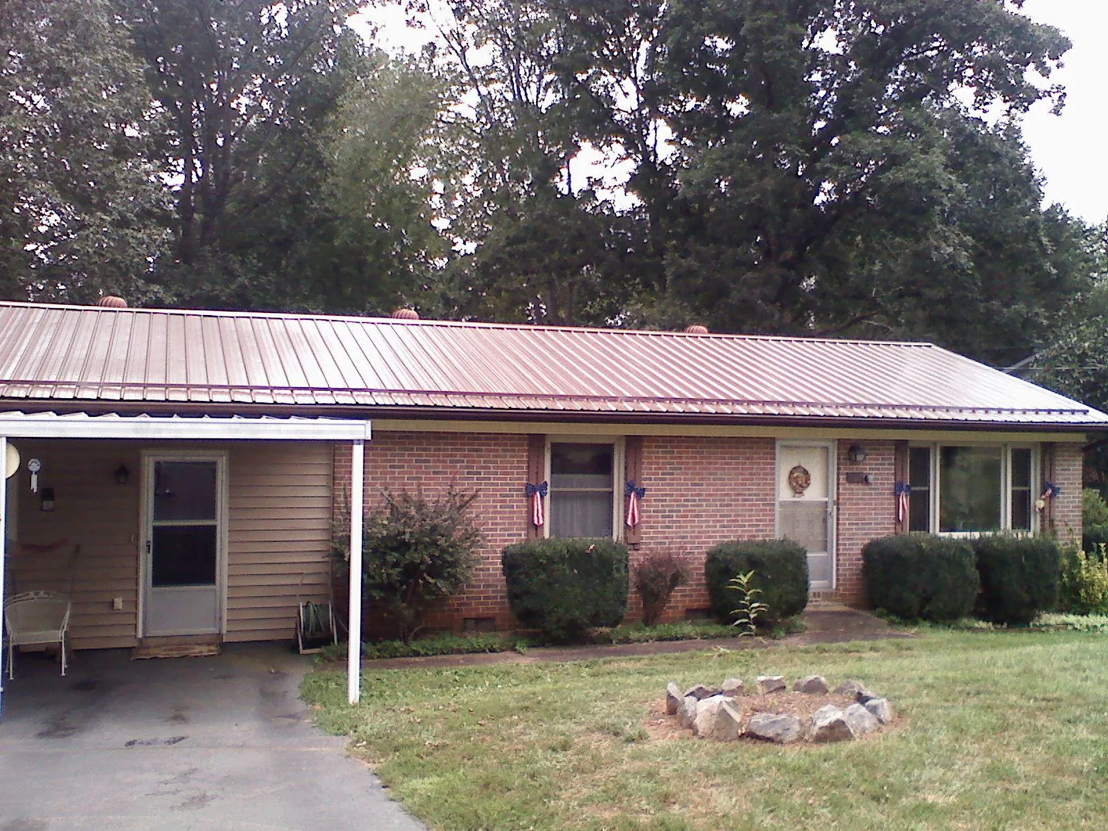 Bronze metal roof and carport on a brick ranch home — Roof Repair work by our crew in Darien Center
